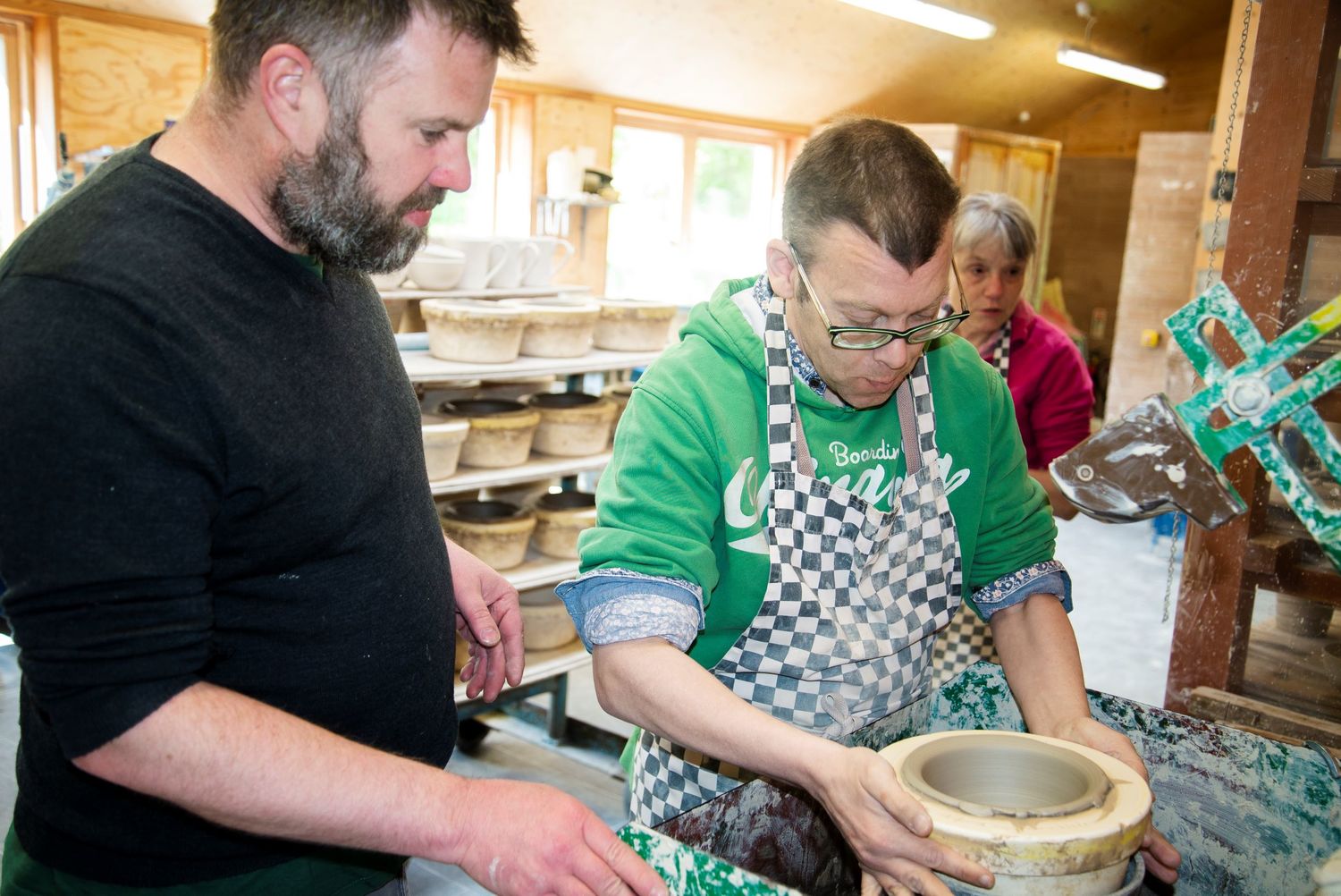 A person we support making pottery on a wheel in a pottery workshop