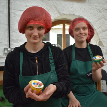 Two people we support holding cupcakes