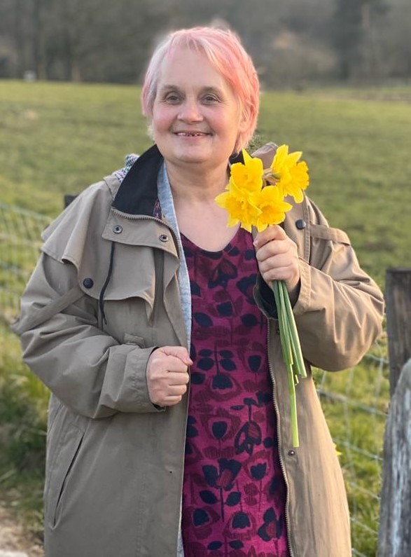 A person we support smiling, holding daffodils