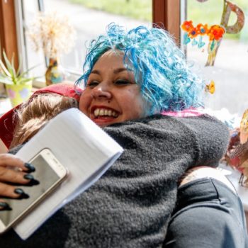 A staff member hugging a community member, smiling