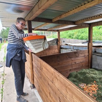 A person we support emptying the law mower grass in a compost heap