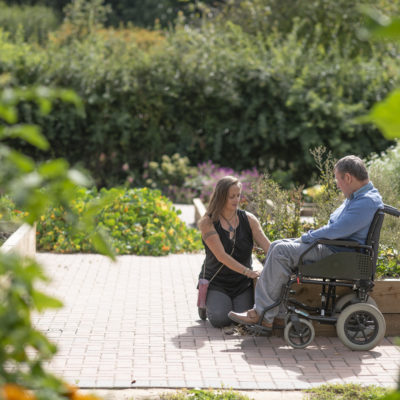 A person we support in a wheelchair with a staff member sitting outside