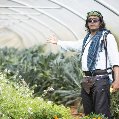 One of the people we support standing in a greenhouse with plants