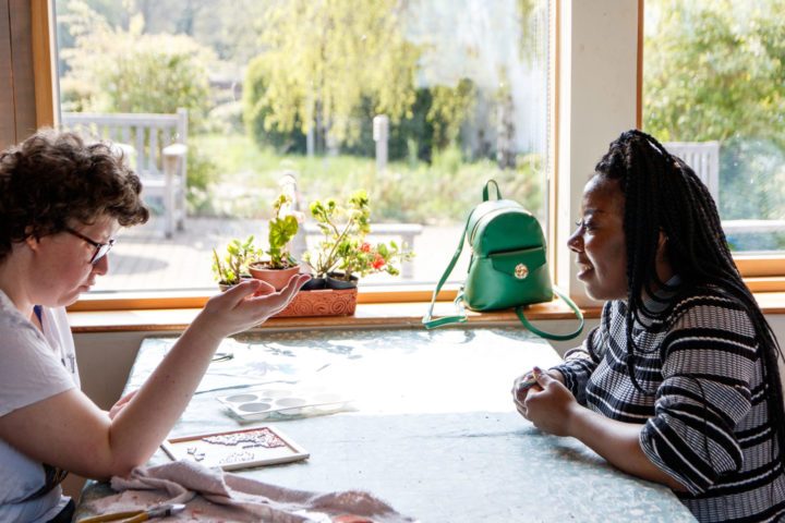 Support worker and person we support sitting at the table completing a puzzle together