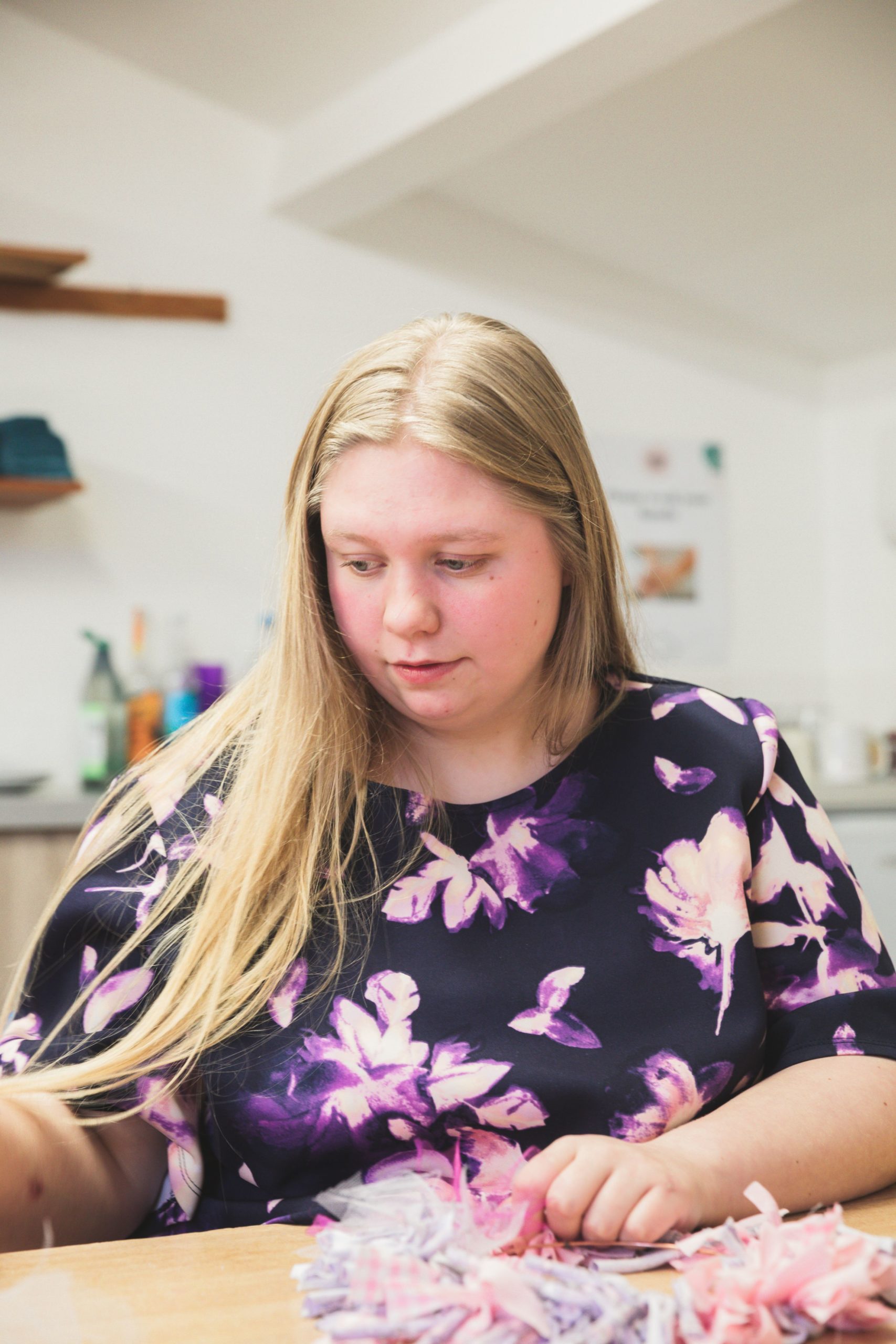 One of the people we support in an arts and crafts workshop holding feathers