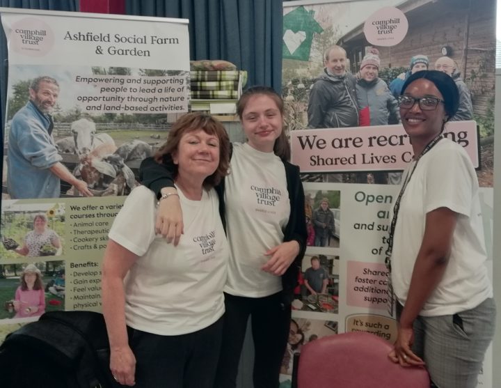 Katie, with two Shared Lives staff from Camphill Village Trust, standing together and smiling at an event