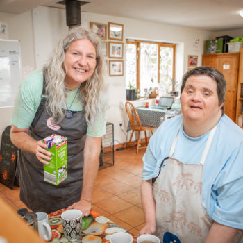 A support worker and person we support making teas and coffees in the kitchen