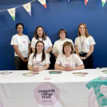 Shared Lives team sitting together at an event wearing Camphill Village Trust t shirts