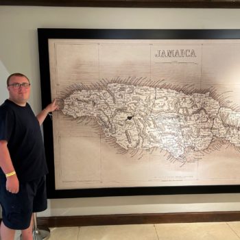 A person we support in Jamaica standing next to a map