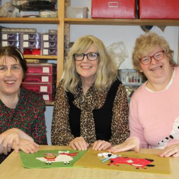 Two people we support in arts and crafts workshop holding their handmade christmas cards in Larchfield