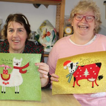 Two people we support holding their handmade christmas cards in Larchfield